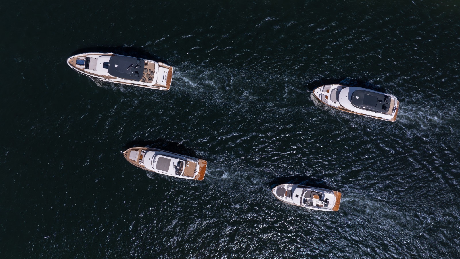 Aerial top-down view of four yachts underway on dark South Florida water