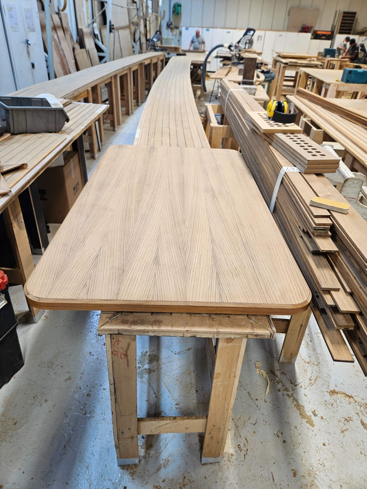 Teak deck panel being crafted in a yacht build workshop — precision marine carpentry